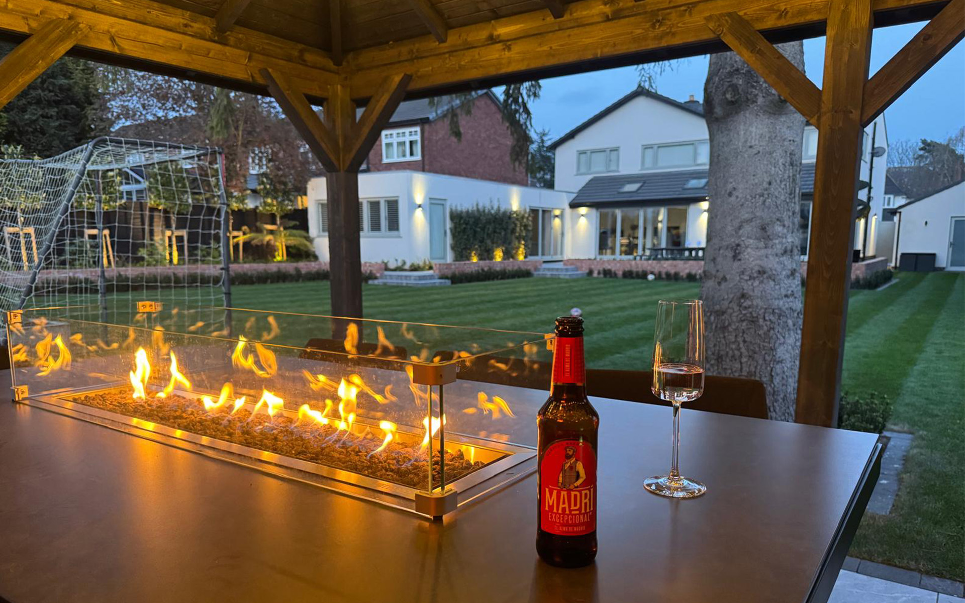 Table with Gas Fire Pit set within Outdoor Garden room overlooking landscaped garden