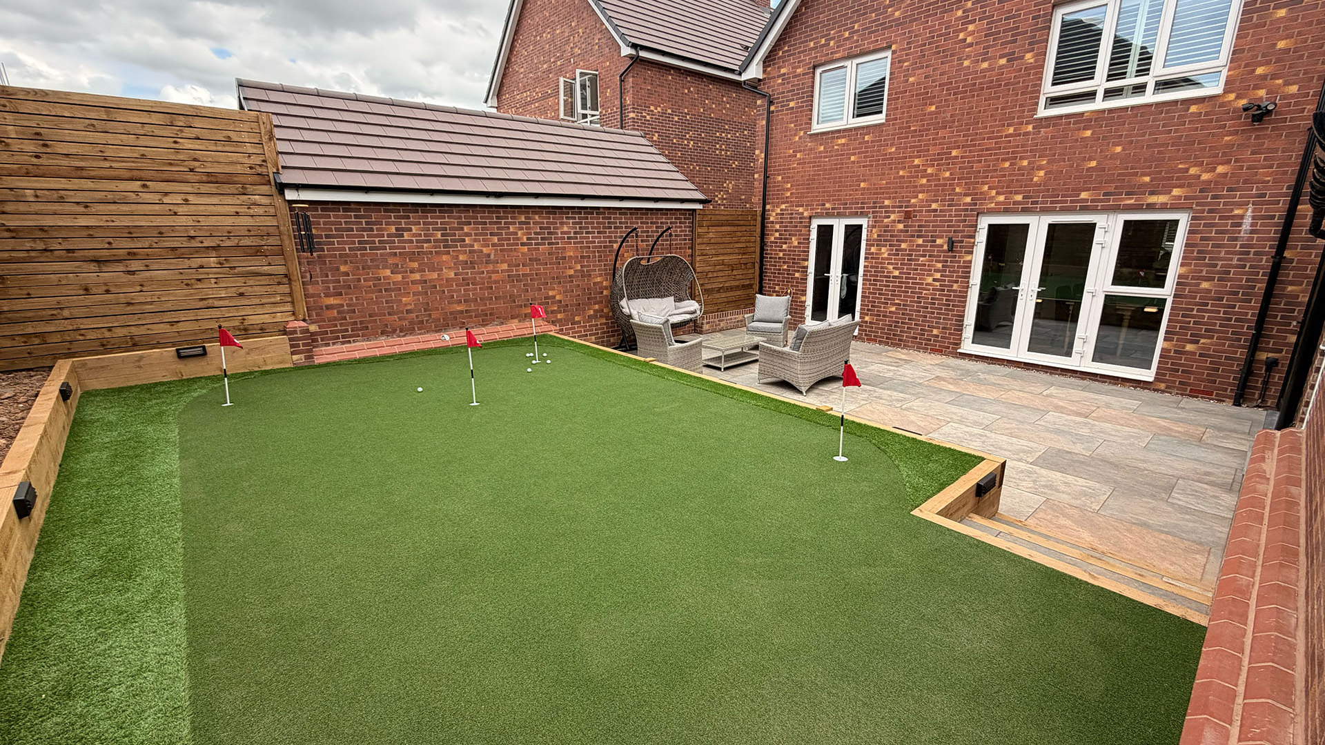 A putting green in a residential garden with multiple flags and holes